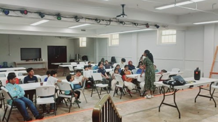 Children engaged in social cultural activities in a decorated classroom setting with colorful bunting and organized seating