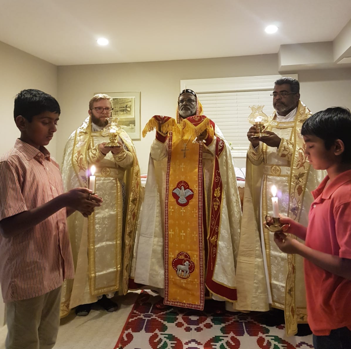 Clergy members in golden vestments during religious ceremony with young participants holding candles