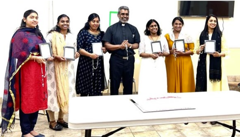 Mothers Forum members in traditional Indian attire receiving certificates from the priest, showcasing their active participation in church activities and community service