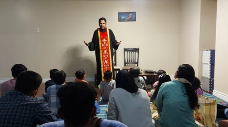 Community prayer meeting with priest in traditional vestments leading a group of parishioners in an intimate gathering